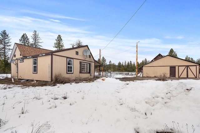 snow covered property with a detached garage and an outdoor structure