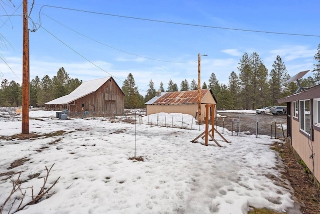 yard covered in snow with a barn, a garage, fence, and an outdoor structure