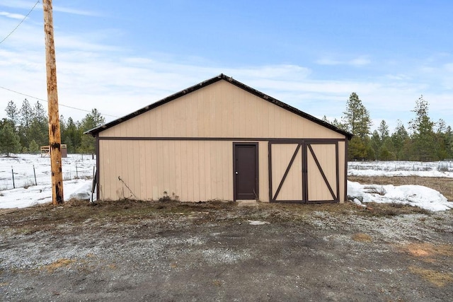 snow covered structure featuring a pole building and an outdoor structure