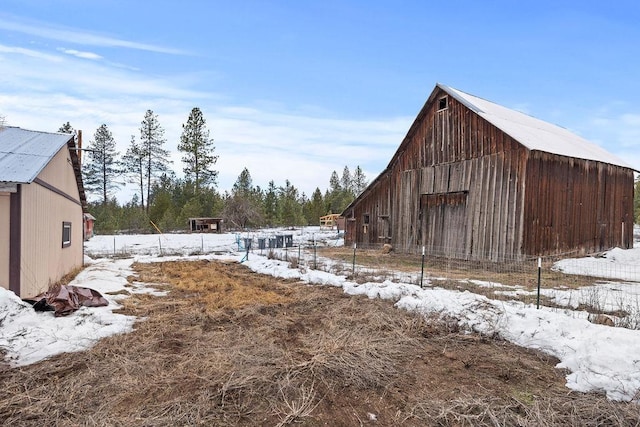 yard covered in snow with an outbuilding, a barn, and fence