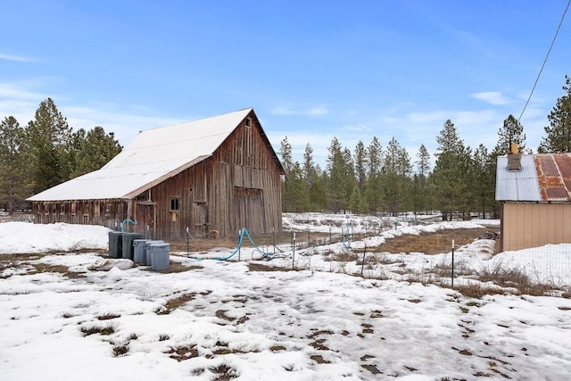 snow covered structure featuring an outdoor structure and a barn