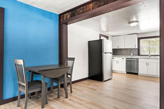 kitchen featuring light wood finished floors, white cabinetry, stainless steel appliances, and a sink