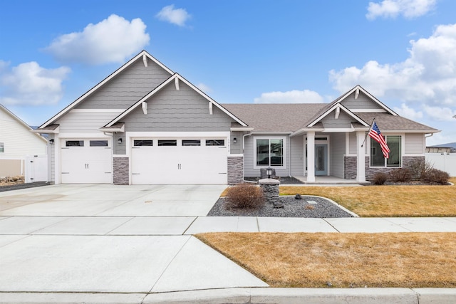 craftsman-style house featuring driveway, a garage, a shingled roof, stone siding, and a front lawn