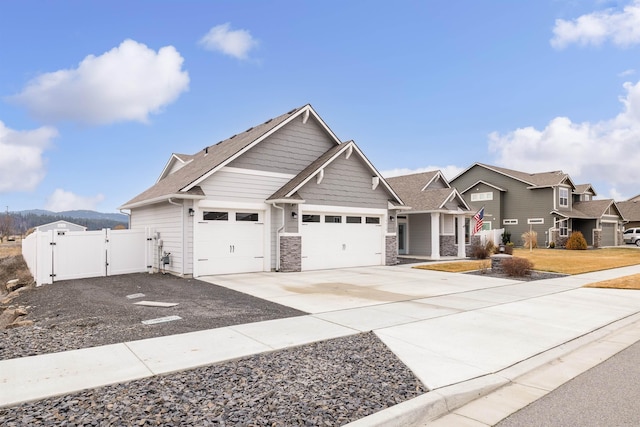 view of front of property with an attached garage, driveway, stone siding, a residential view, and a gate