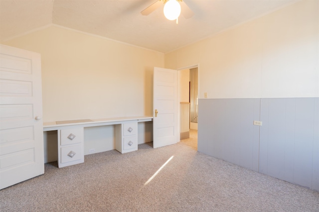 unfurnished office featuring carpet, a ceiling fan, vaulted ceiling, and built in desk