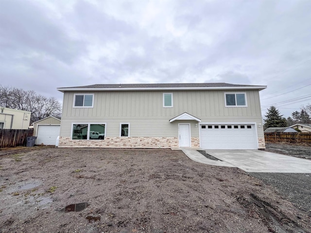 traditional-style home with a garage, stone siding, fence, and board and batten siding