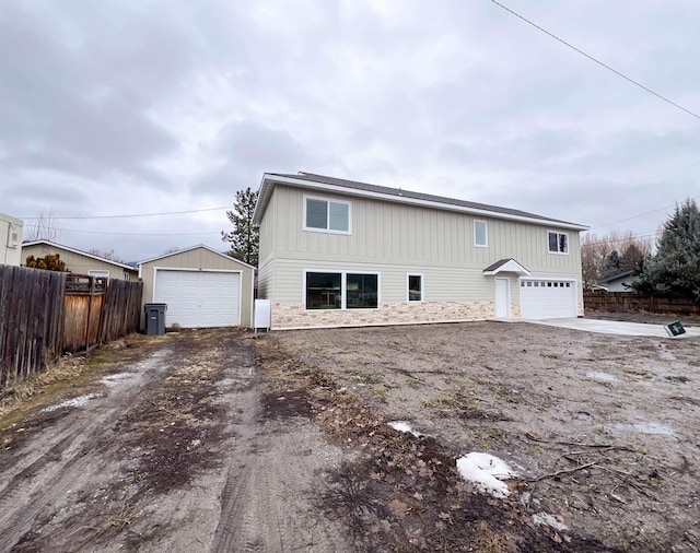 exterior space with driveway, a garage, fence, and an outdoor structure