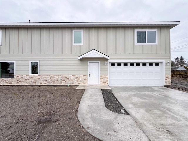 view of front of home featuring a garage, stone siding, and driveway