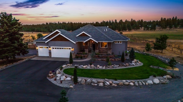 view of front of property with driveway, stone siding, a garage, and a yard