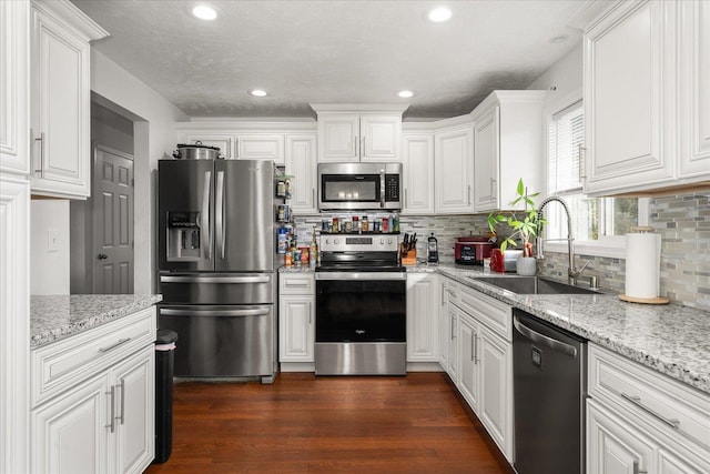 kitchen with white cabinets, appliances with stainless steel finishes, dark wood-type flooring, and a sink