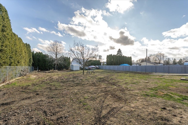 view of yard with an outdoor structure, fence, and a storage shed