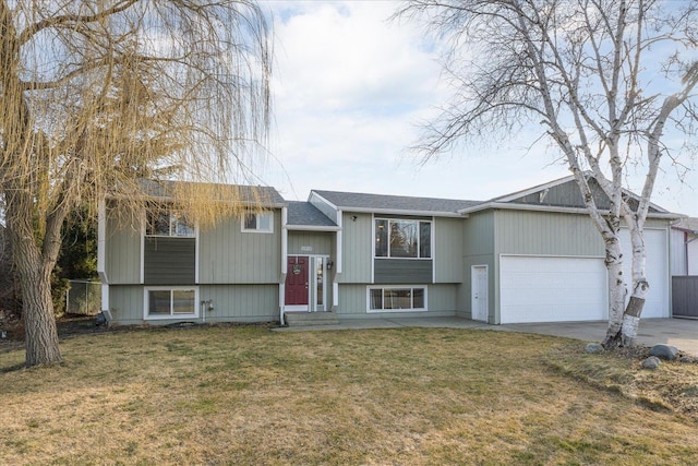 bi-level home with concrete driveway, a front lawn, and an attached garage