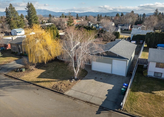 view of front of house featuring a mountain view, a garage, concrete driveway, a residential view, and a front yard