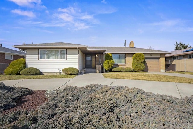 view of front of house featuring a front yard, concrete driveway, a chimney, and an attached garage