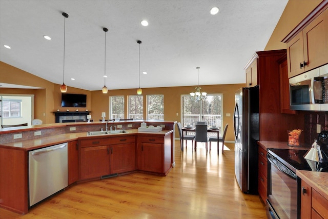 kitchen with pendant lighting, a sink, light wood finished floors, and black appliances