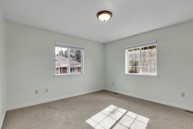 spare room featuring carpet, visible vents, and baseboards