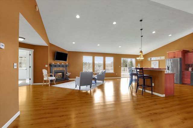 kitchen featuring stainless steel fridge with ice dispenser, light wood-style flooring, a kitchen breakfast bar, open floor plan, and a fireplace