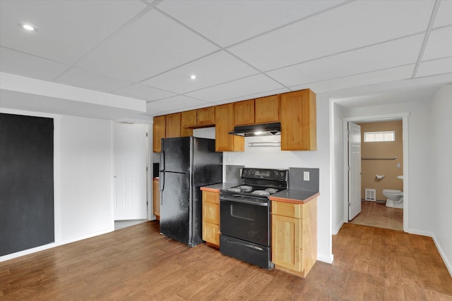 kitchen with black appliances, light wood-style floors, visible vents, and under cabinet range hood