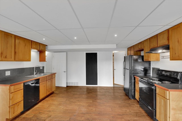 kitchen with dark countertops, visible vents, light wood-type flooring, under cabinet range hood, and black appliances