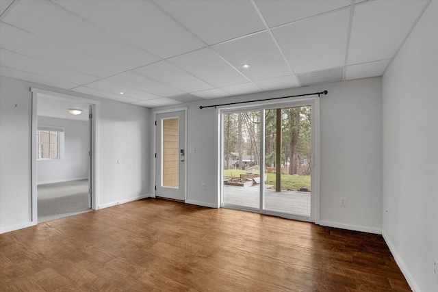 unfurnished room featuring baseboards, a drop ceiling, and wood finished floors