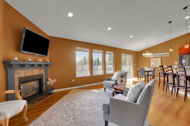 living area with light wood-type flooring, vaulted ceiling, a fireplace, and baseboards