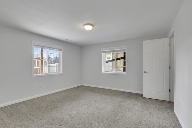 carpeted empty room featuring baseboards, visible vents, and a healthy amount of sunlight