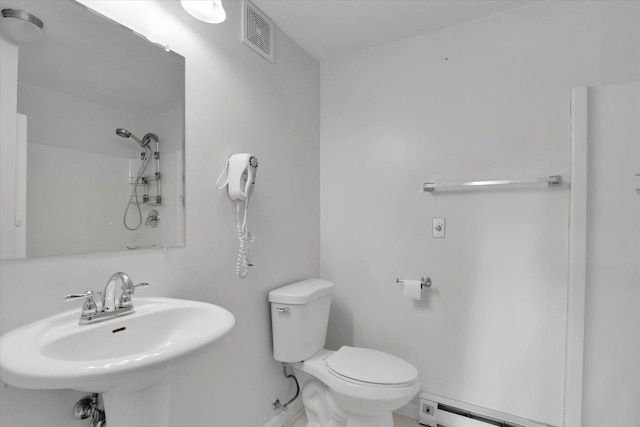 bathroom featuring visible vents, a shower, toilet, baseboard heating, and a sink