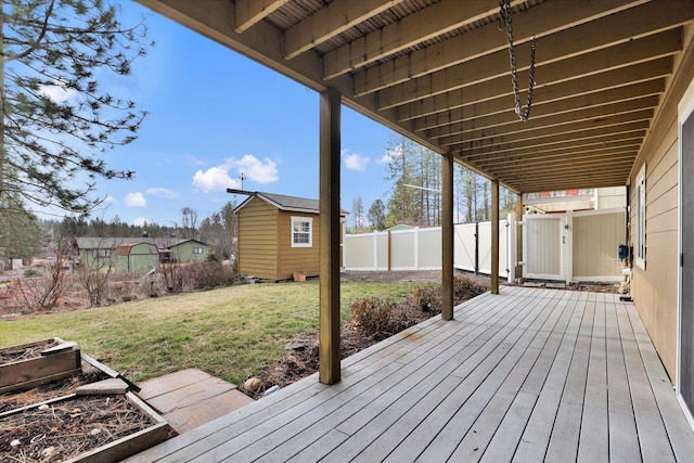 deck with a shed, a lawn, an outdoor structure, and a fenced backyard