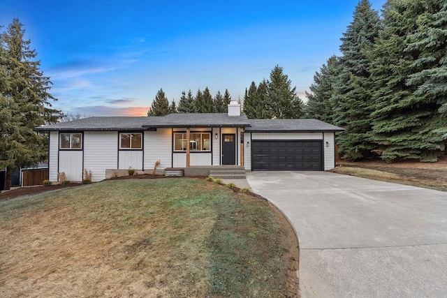 ranch-style home featuring driveway, a yard, a chimney, and an attached garage