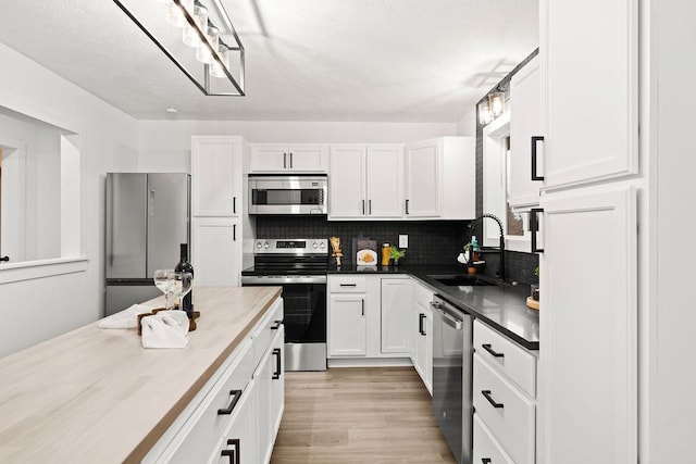 kitchen with stainless steel appliances, white cabinetry, a sink, and decorative backsplash