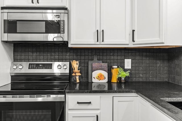 kitchen featuring stainless steel appliances, tasteful backsplash, dark stone countertops, and white cabinetry