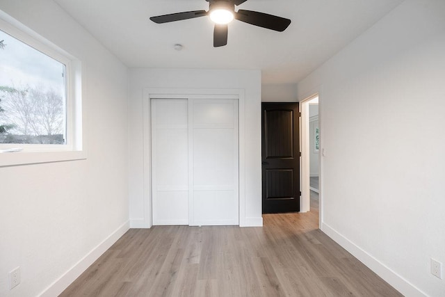 unfurnished bedroom featuring a ceiling fan, a closet, light wood-style flooring, and baseboards