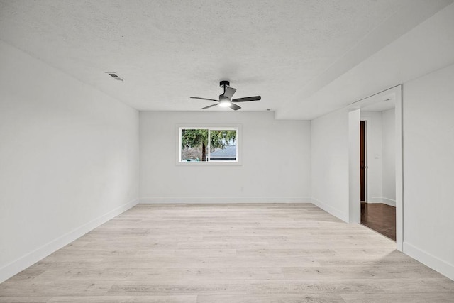 empty room featuring light wood-style flooring, visible vents, and a textured ceiling