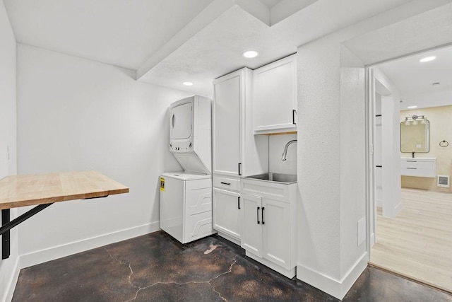 laundry room featuring stacked washer and dryer, recessed lighting, visible vents, a sink, and baseboards