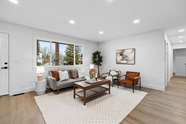 living area with light wood-type flooring, visible vents, baseboards, and recessed lighting