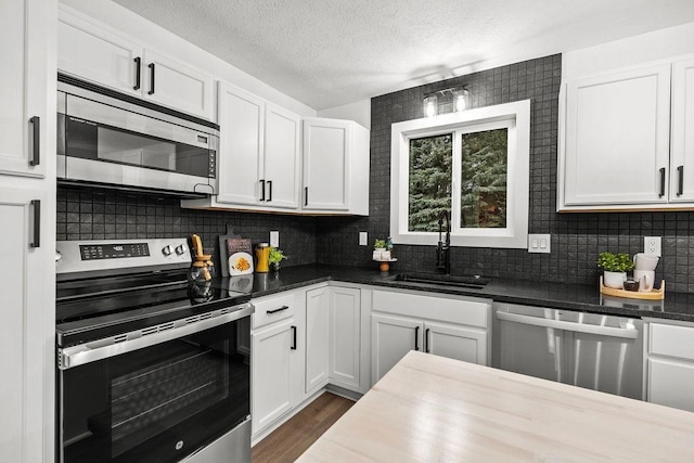 kitchen featuring backsplash, white cabinetry, stainless steel appliances, and a sink