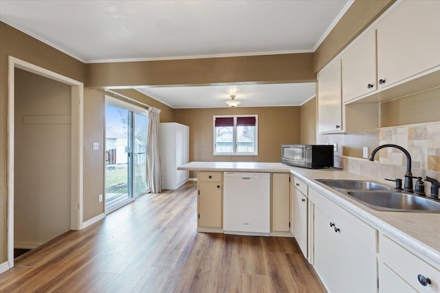 kitchen with white dishwasher, a peninsula, a sink, light wood finished floors, and stainless steel microwave