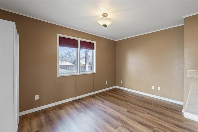 spare room with crown molding, baseboards, and wood finished floors