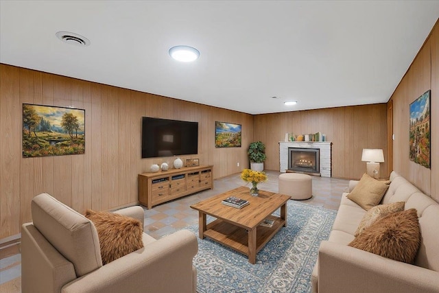 living room featuring light floors, a brick fireplace, visible vents, and wooden walls