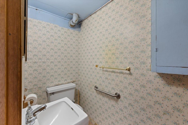 bathroom featuring electric panel, a sink, toilet, and wallpapered walls