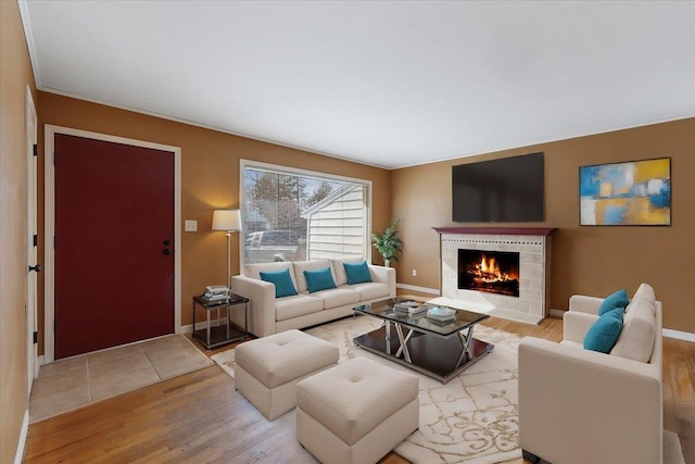 living area featuring baseboards, a tiled fireplace, and wood finished floors