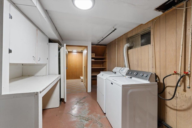 laundry area featuring cabinet space, wooden walls, and separate washer and dryer