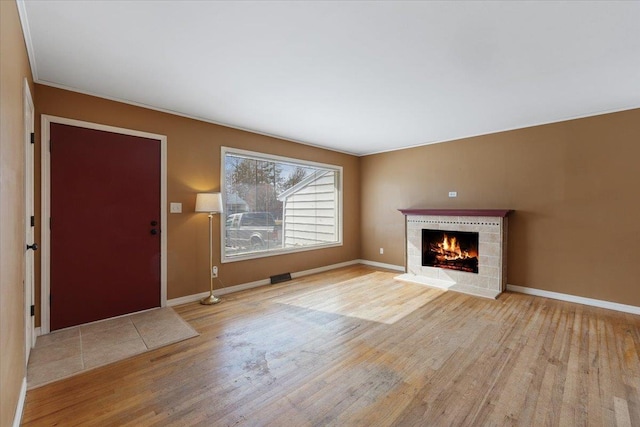 unfurnished living room featuring a fireplace, baseboards, and wood finished floors