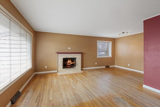 unfurnished living room with light wood-style floors, baseboards, a fireplace, and visible vents