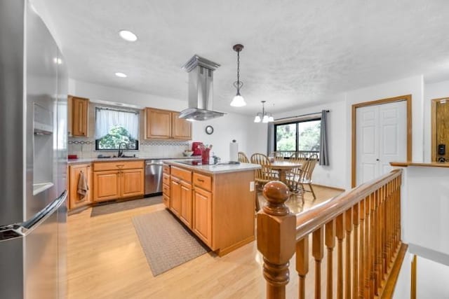 kitchen featuring stainless steel appliances, decorative backsplash, light wood finished floors, and island range hood