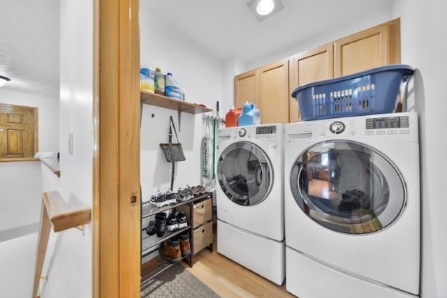 clothes washing area with light wood-type flooring, cabinet space, and washer and clothes dryer