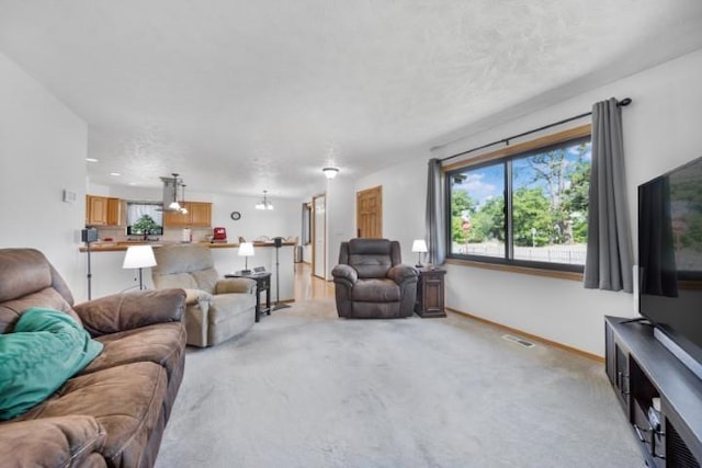 living room with a chandelier, light colored carpet, visible vents, and baseboards