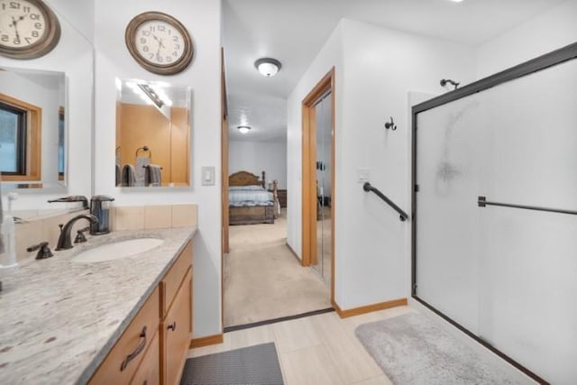 ensuite bathroom featuring a stall shower, connected bathroom, vanity, and baseboards