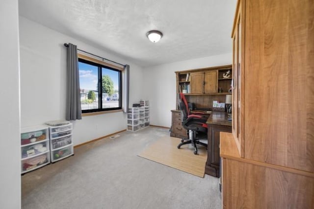 office featuring light carpet, a textured ceiling, and baseboards