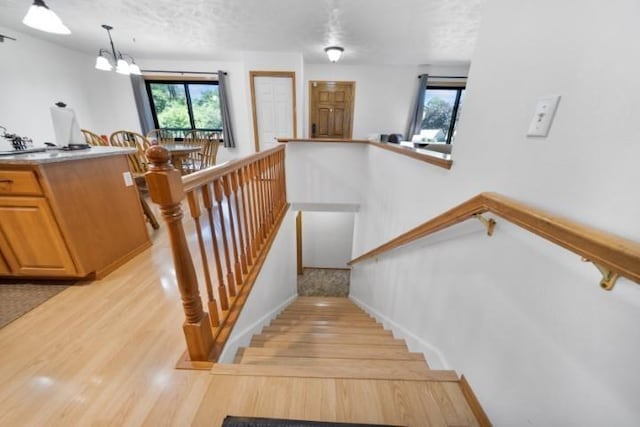 stairway featuring an inviting chandelier, a textured ceiling, and wood finished floors